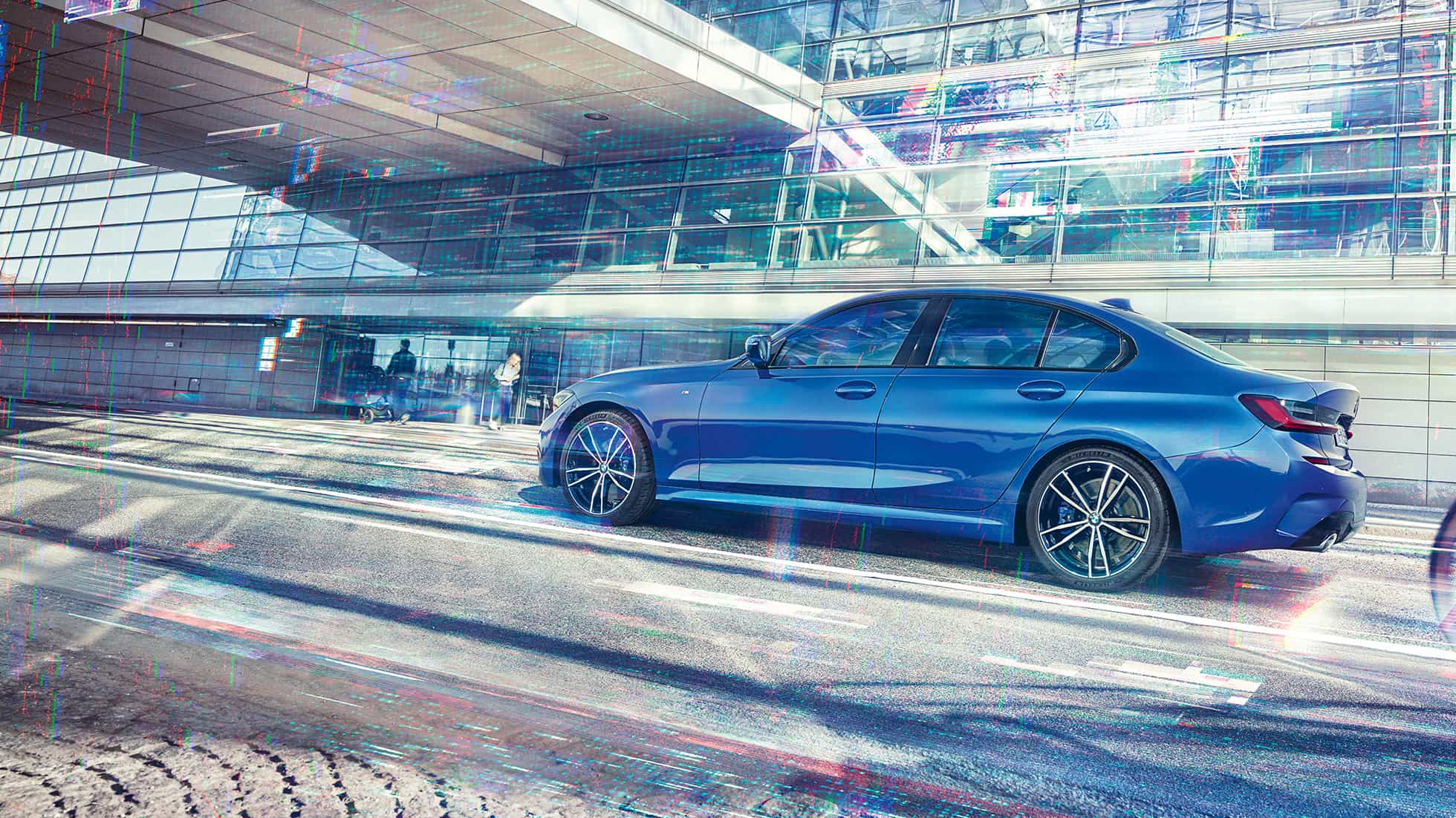 BMW 3 Series, side view. Still shot of the BMW 3 Series from the side on the day in front of a glass building.